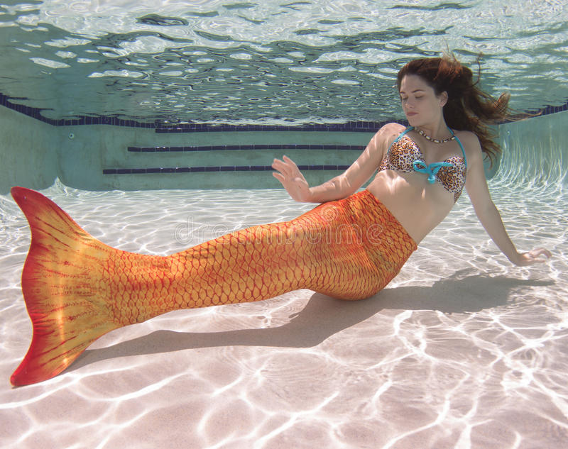Frau im Wasser mit einer orangefarbenen Meerjungfrauenflosse
