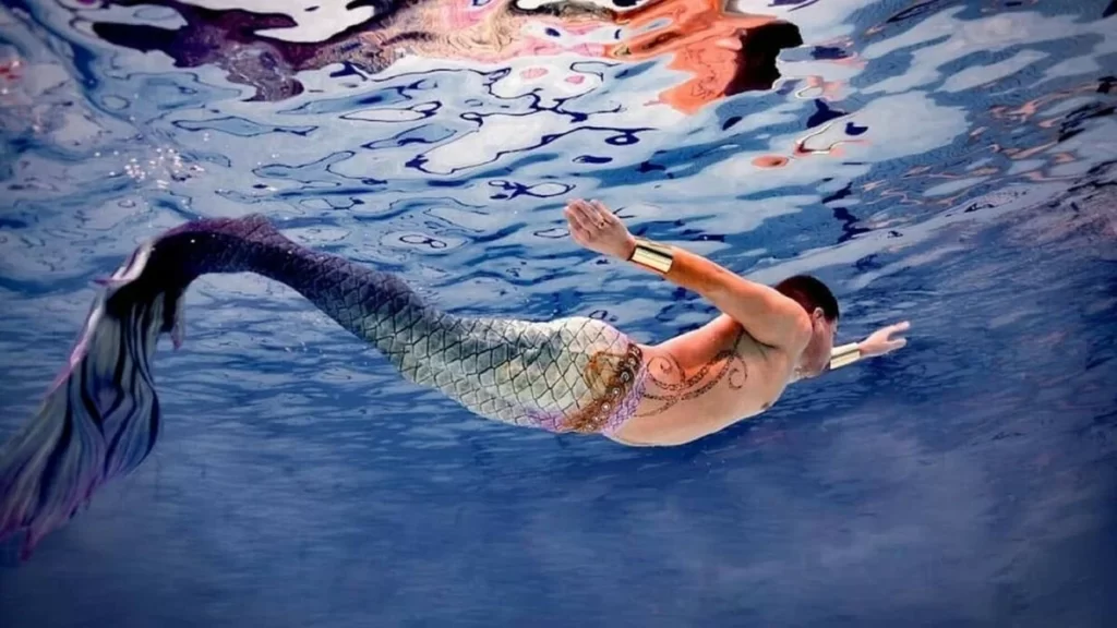 Mann, der als Meerjungfrau schwimmt